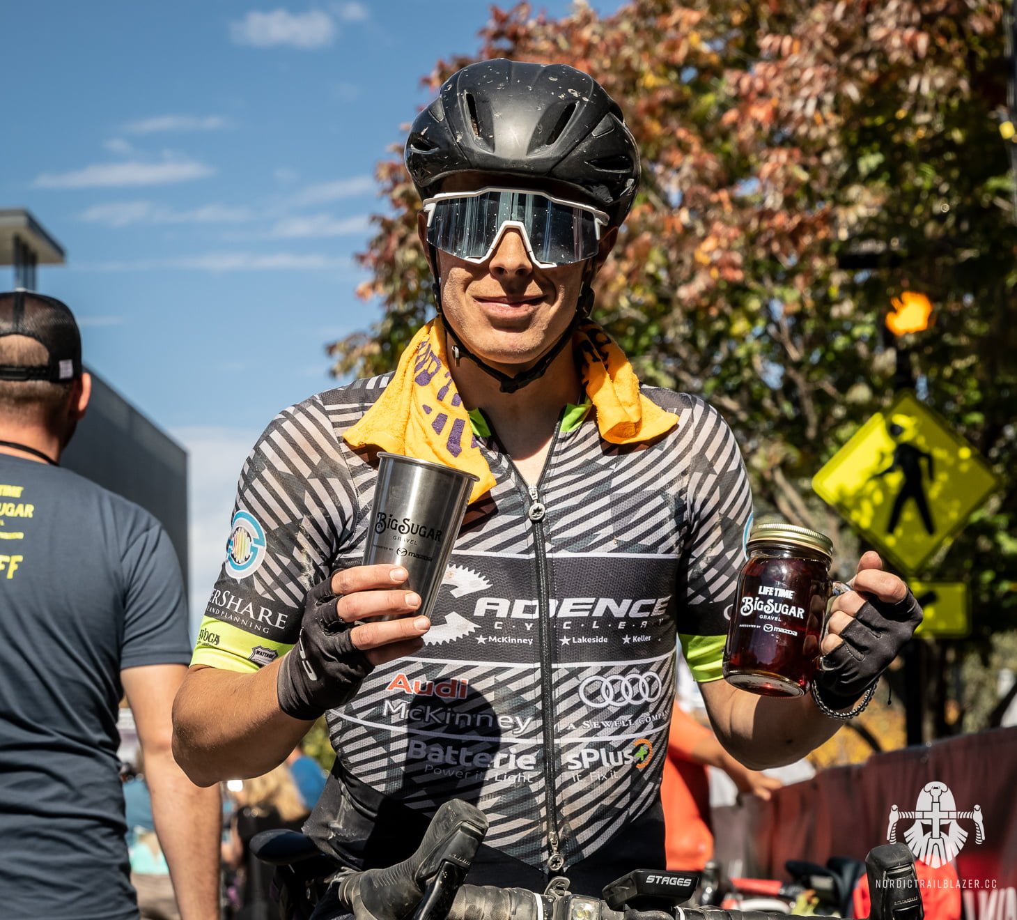 Cyclist holding a cup and a maple sirup can 